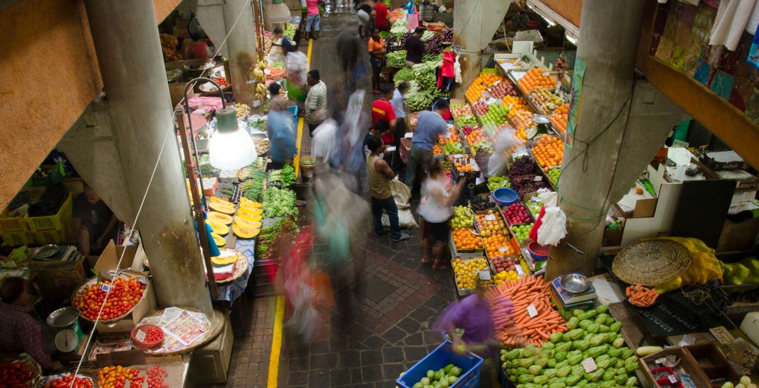 People shopping at an outsice marketplace for fruit