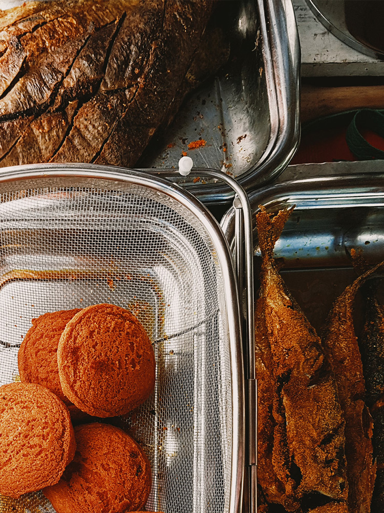 Circular acarajé, surrounded by other delicacies, such as fried fish and passarinha (fried cow spleen)