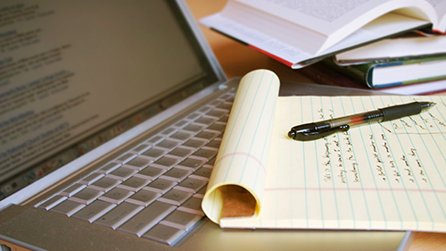 Legal pad with notes written, laying in front of a computer